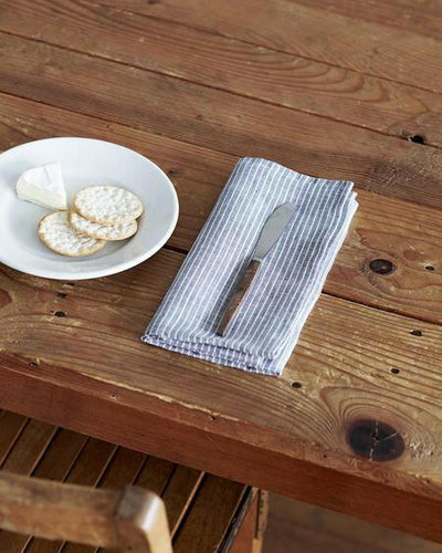 Serviette de table en lin gris clair et rayures fines blanches.